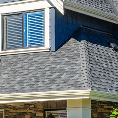 Modern home exterior featuring a gray shingle roof and large windows with blue blinds.