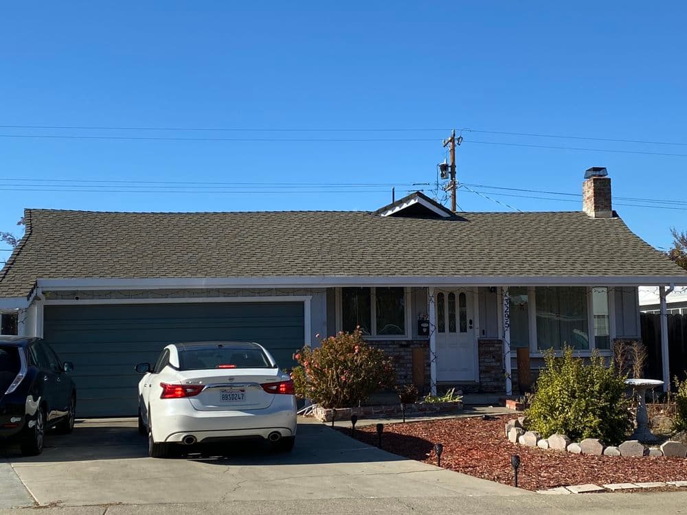 Single-story home with a blue garage, driveway, and landscaped front yard under clear blue sky.