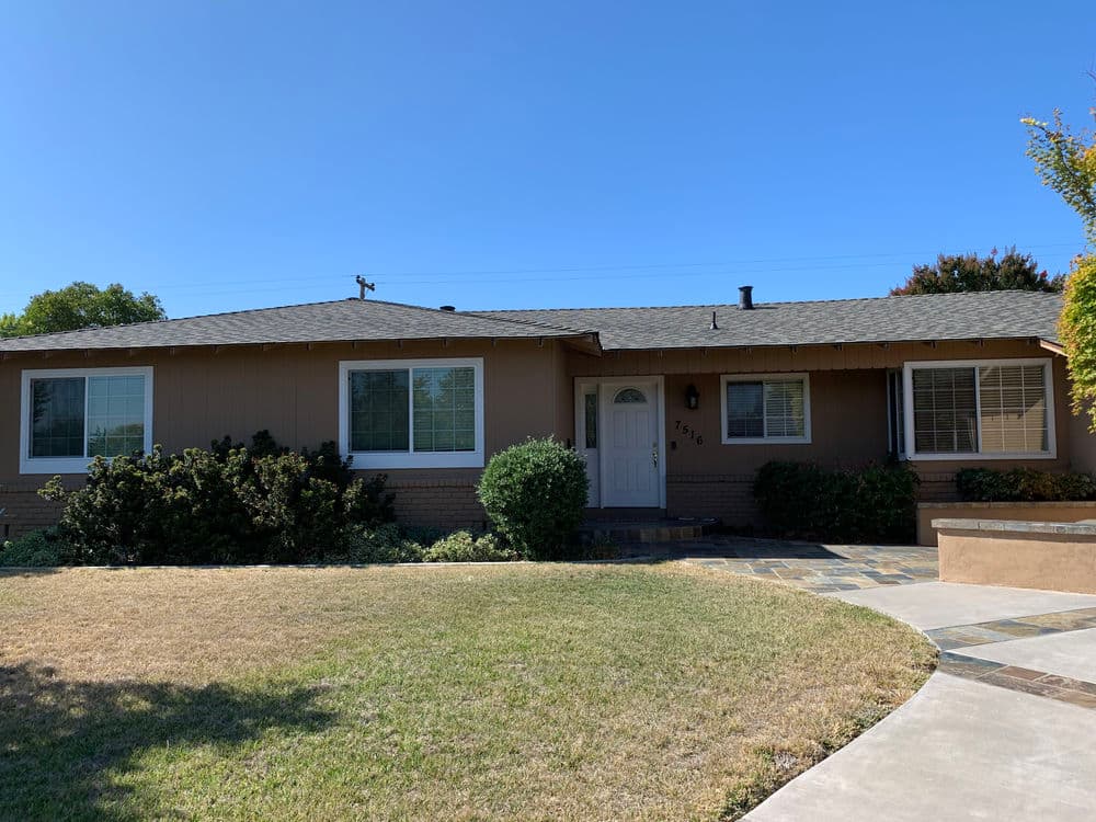 Single-story home with green lawn, large windows, and a welcoming front porch.