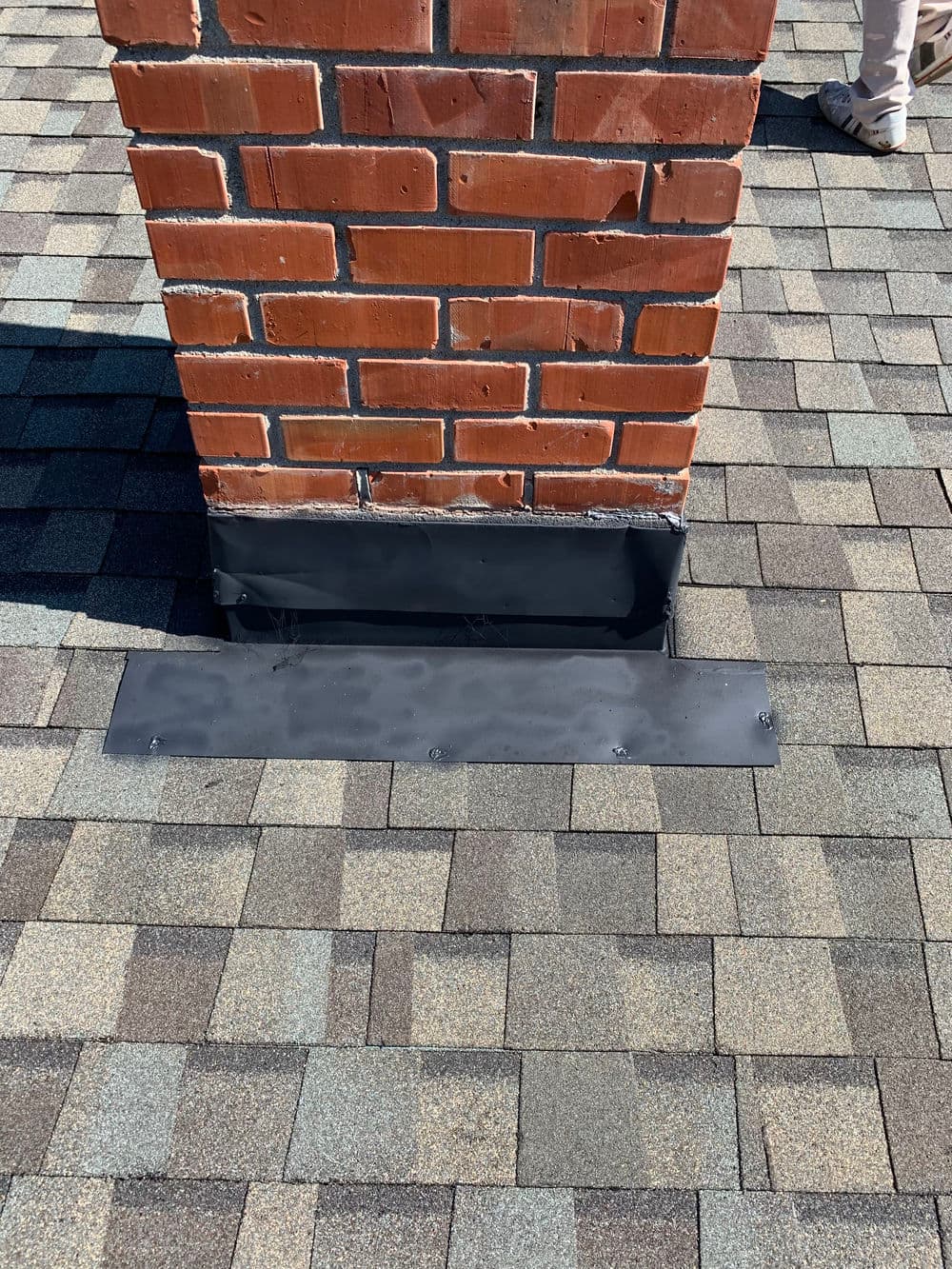 Chimney flashing installation on a shingled roof, ensuring waterproofing and protection.