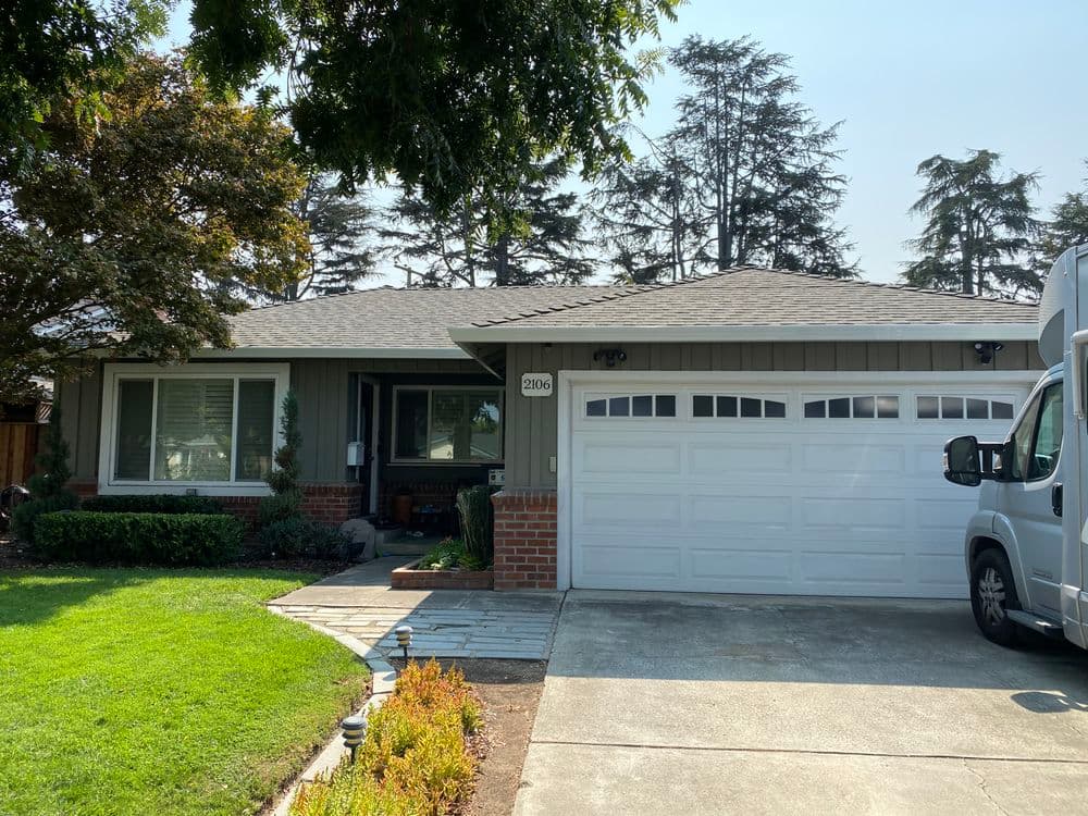 Single-story suburban home with a gray exterior, white garage door, and landscaped front yard.