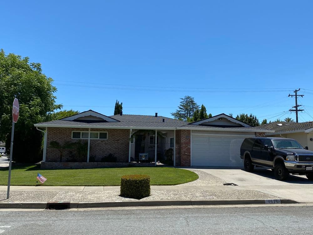 Single-story brick home with a front lawn and black SUV parked in the driveway.