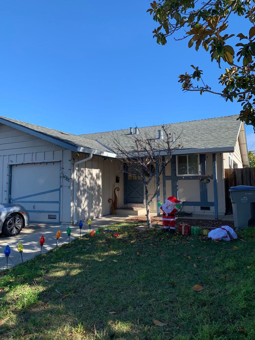 Festive home with Santa decoration, holiday lights, and clear blue sky.